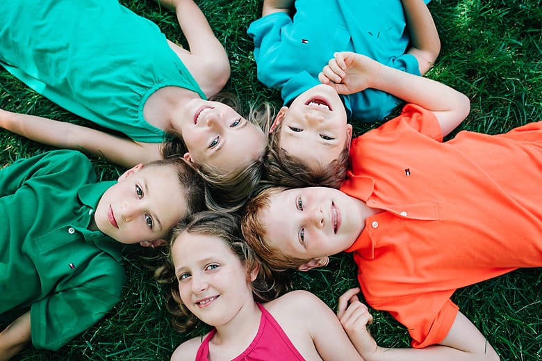 Five children lying on the ground, happily looking at you.
