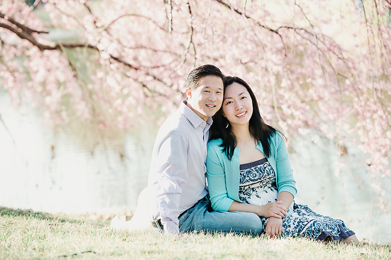 a couple is sitting under the cherry blossom tree