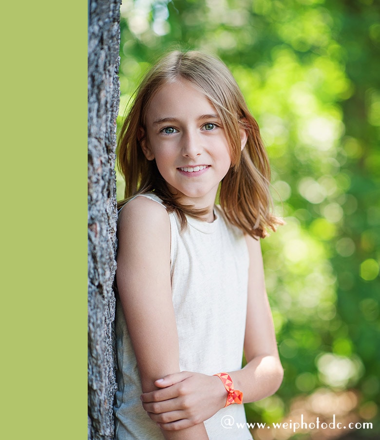 a girl with green eyes wearing green dress standing by the tree