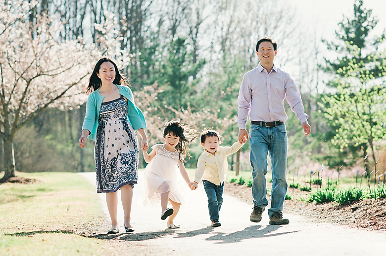 A happy family of four walking hand in hand, moving forward together.