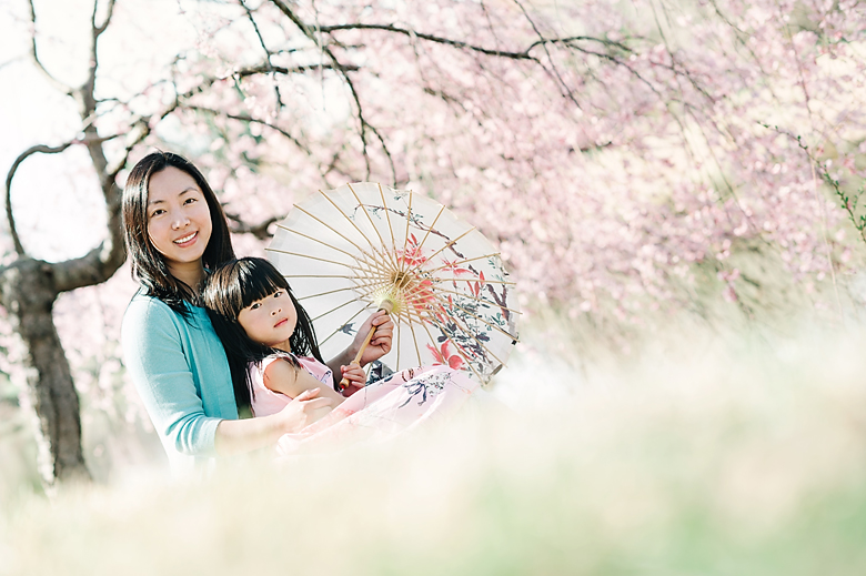 mother and daughter are sitting under the cherry blosoom tree